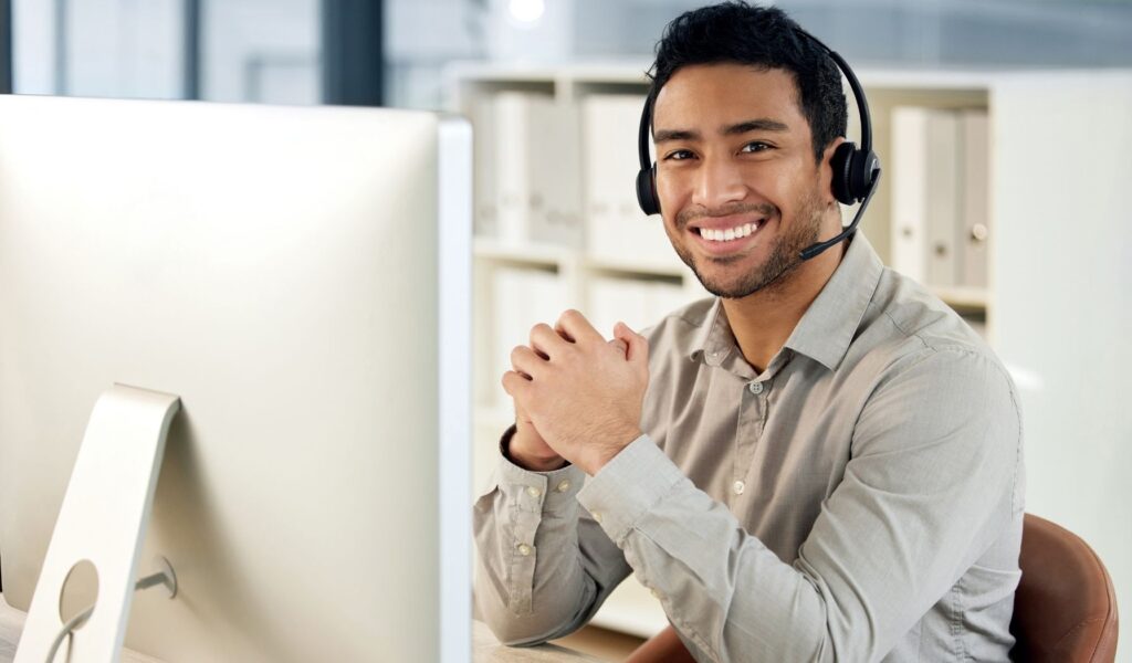 Smiling man with a headset working in front of a computer